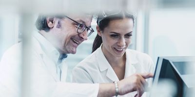 Man and Woman in lab coats viewing something on a monitor