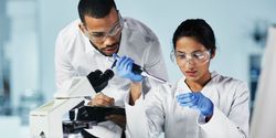 A man looks on as a woman pipets into a container