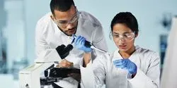 A man looks on as a woman pipets into a container