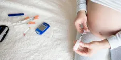 A pregnant woman holding a glucose monitoring device
