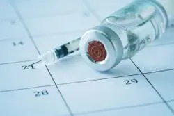 Image of a syringe next to a vial of COVID-19 vaccine