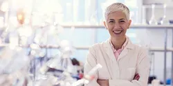 Clinical laboratory personnel wearing a lab coat smiling in a lab