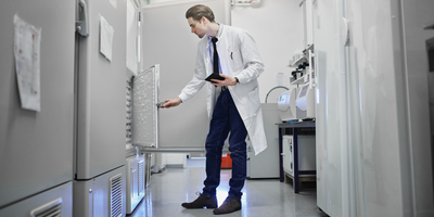 clinical laboratory technician inspecting ultralow temperature freezer