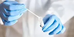 A person wearing personal protective equipment putting a nasal SARS-CoV-2 swab into a tube