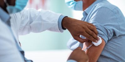 A clinician gives a patient a sars-cov-2 vaccination in the upper arm