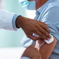 A clinician gives a patient a sars-cov-2 vaccination in the upper arm
