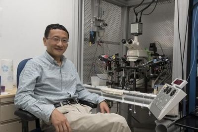 Photo of J. Julius Zhu, PhD, sitting at the new biosensor microscope at his lab at the University of Virginia Health System.