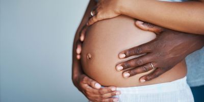 Photo of a pregnant Black woman holding her baby bump