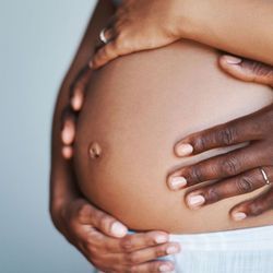 Photo of a pregnant Black woman holding her baby bump