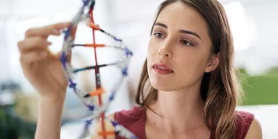 Photo of a woman looking at a large-scale model of DNA