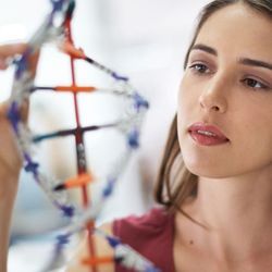 Photo of a woman looking at a large-scale model of DNA