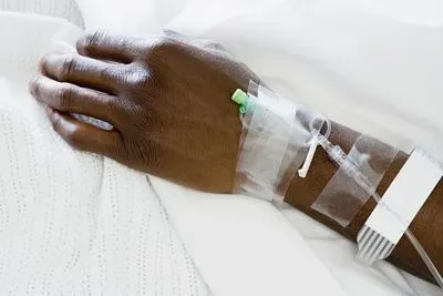 Photo of a Black cancer patient's hand with an IV tube