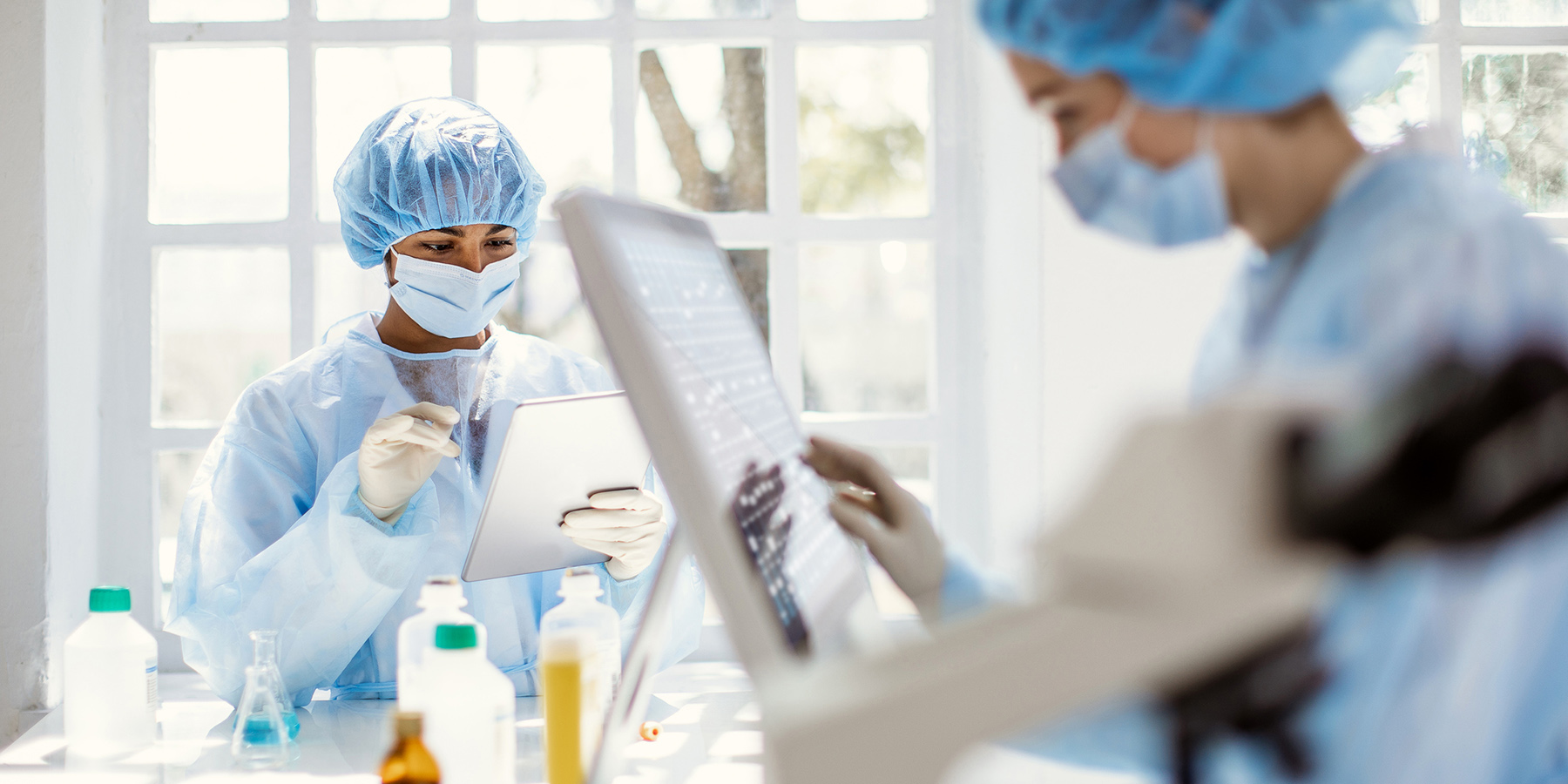 Photo of laboratory professionals wearing PPE in a science lab near a window