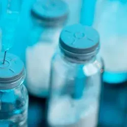 Photo of a syringe sticking out of a vial of COVID-19 vaccine