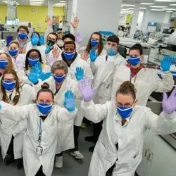 Photo of clinical lab professionals wearing PPE and waving at the camera