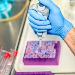 Photo of a clinical lab professional wearing PPE and holding a pipette preparing samples for flow cytometry