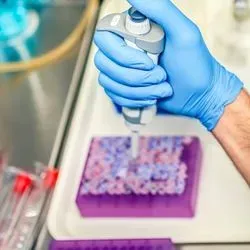Photo of a clinical lab professional wearing PPE and holding a pipette preparing samples for flow cytometry