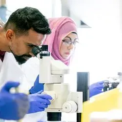 Photo of two laboratory professionals wearing PPE and working at a lab bench
