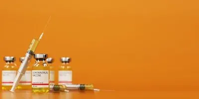 Photo of five vials of Pfizer-BioNTech's covid-19 vaccine against an orange background
