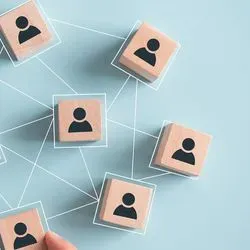 Photo of wooden blocks with an illustration of a person on them connected with white dotted lines in a network