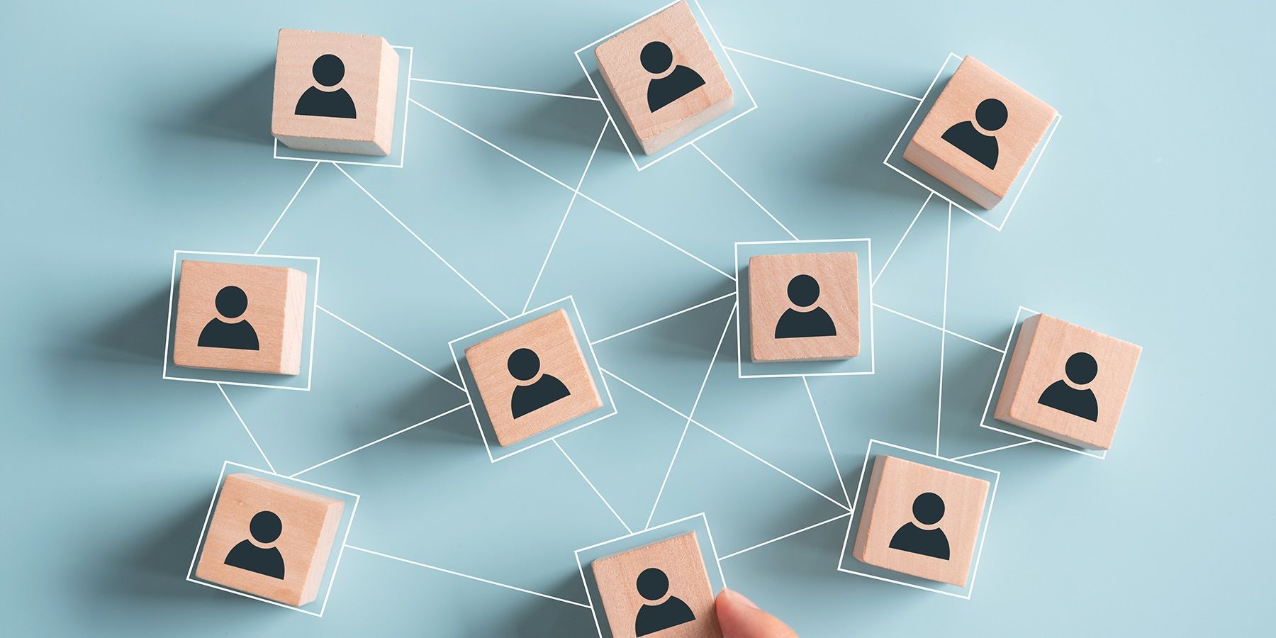 Photo of wooden blocks with an illustration of a person on them connected with white dotted lines in a network