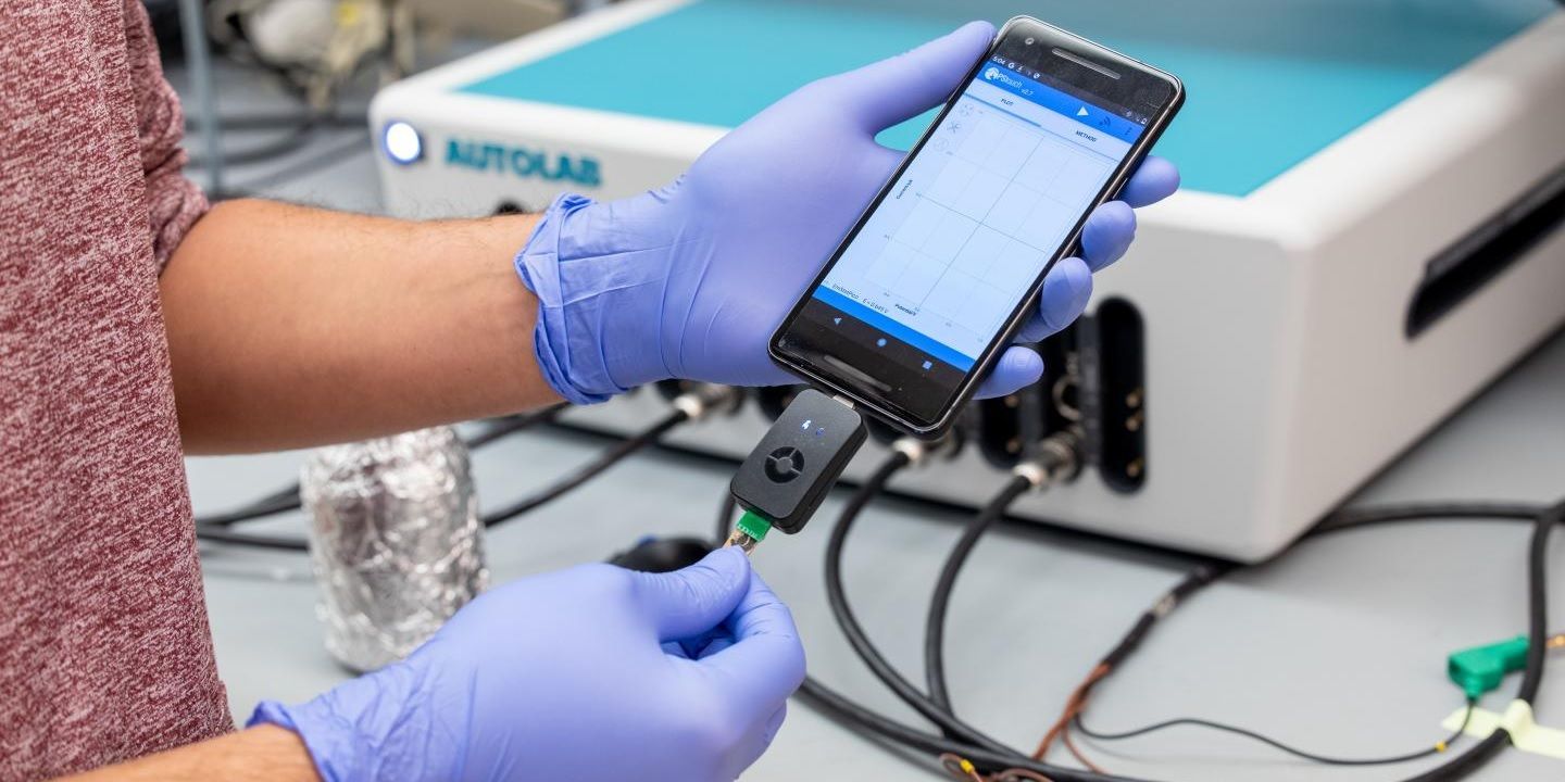 Laboratory professional wearing gloves holds the rapid COVID-19 biosensor test in their hands