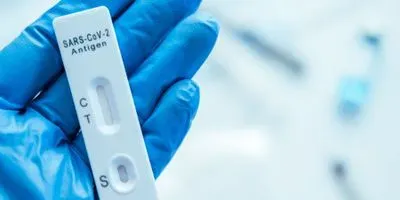 Photo of a SARS-CoV-2 antigen test in the palm of a gloved hand