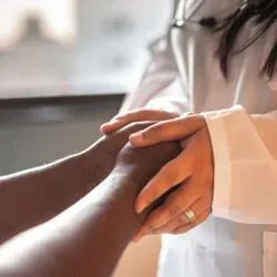 Photo of a laboratory professional holding the hands of a patient