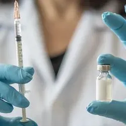 Clincal professional wearing PPE holding an influenza vaccine