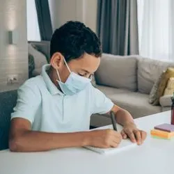 Photo of two children wearing surgical masks sitting a kitchen table