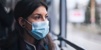Women in mask looking out window