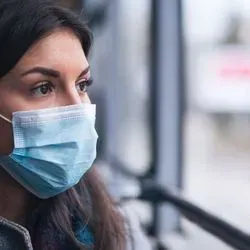 Women in mask looking out window