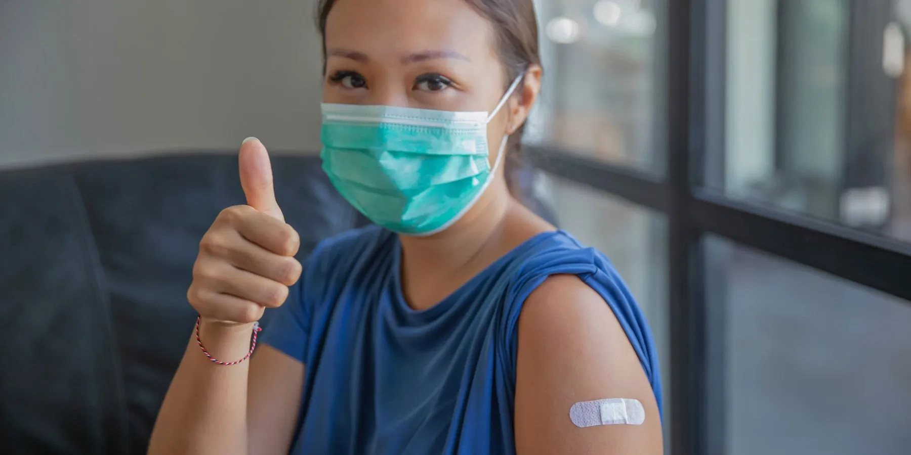 Woman smiling and giving thumbs up after COVID-19 vaccination