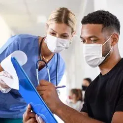 Young adult man signing paperwork at hospital