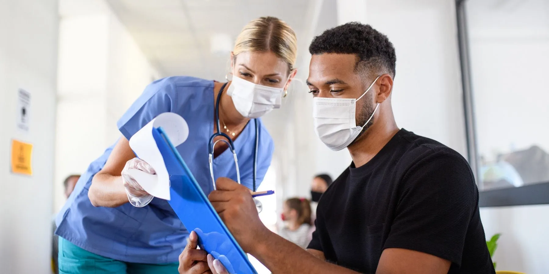 Young adult man signing paperwork at hospital