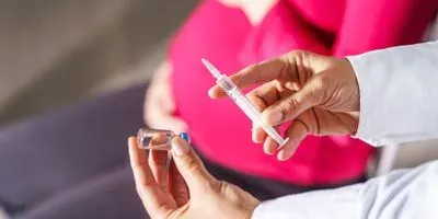Image of a pregnant woman getting a vaccine from a medical professional