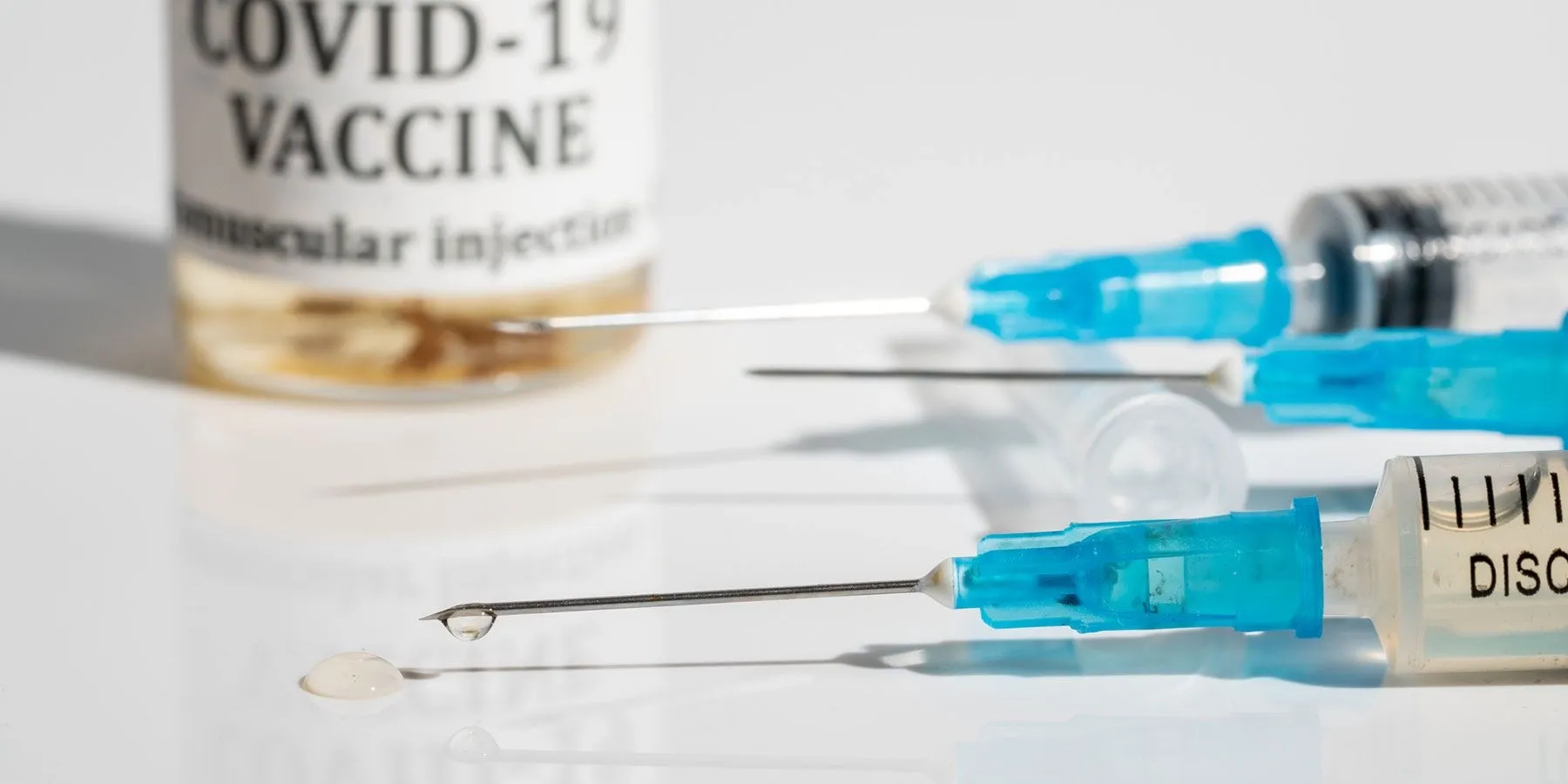 Image of three needles and a bottle of COVID-19 vaccine