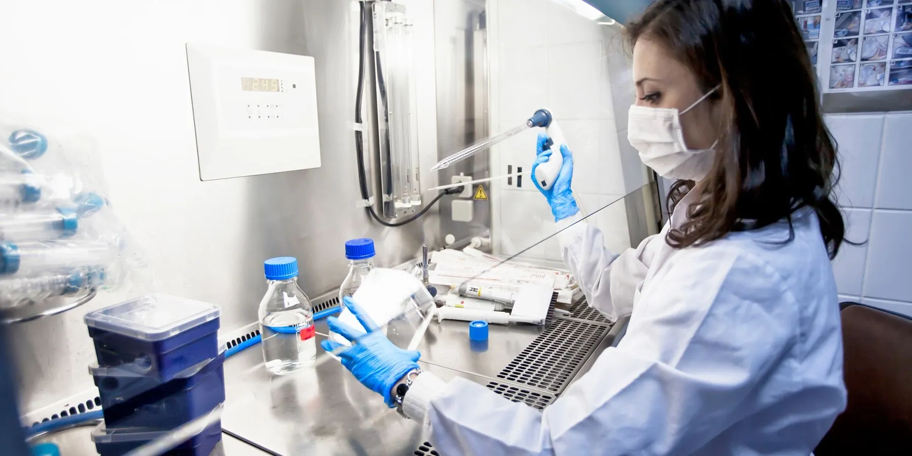 A female clinical lab professional wearing PPE pipettes samples in the lab