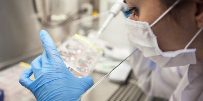 Photo of a clinical lab professional wearing PPE and pipetting CAR T cell therapies