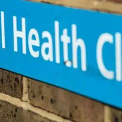 Image of a sign for a sexual health clinic on a brick wall