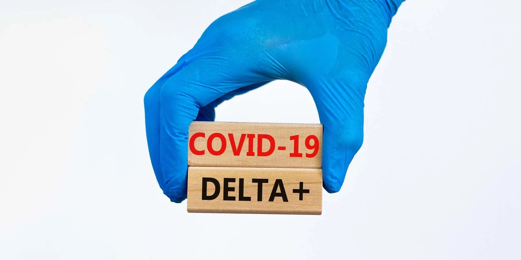 Gloved hand holding blocks that say COVID-19 and DELTA +