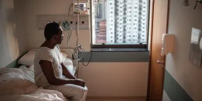 Black man looking out hospital window from his hospital bed