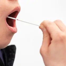 A patient swabs their cheek for a COVID-19 and influenza test.