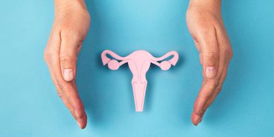 Woman's hands cupped around a paper cut out of a uterus