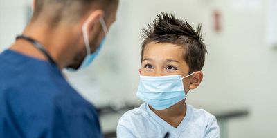A child speaking with a health care professional while wearing a mask