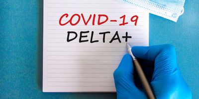 Gloved hand writing COVID-19 Delta+ on a notepad