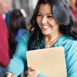 A women holding a clipboard shakes someones hand