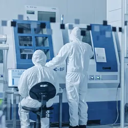 Photo of two clinical lab workers wearing PPE in a cell and gene therapy manufacturing facility