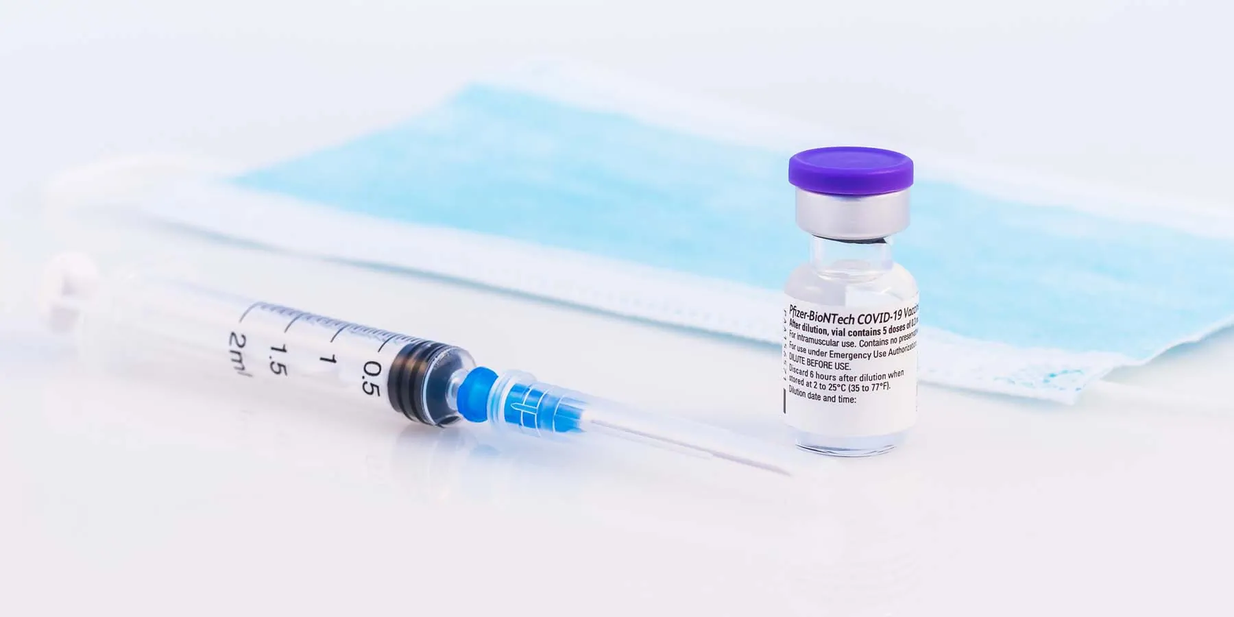 Image of a needle, face mask, and vaccine bottle