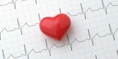 A ruber heart on paper that has a heart rhythme drawn on it